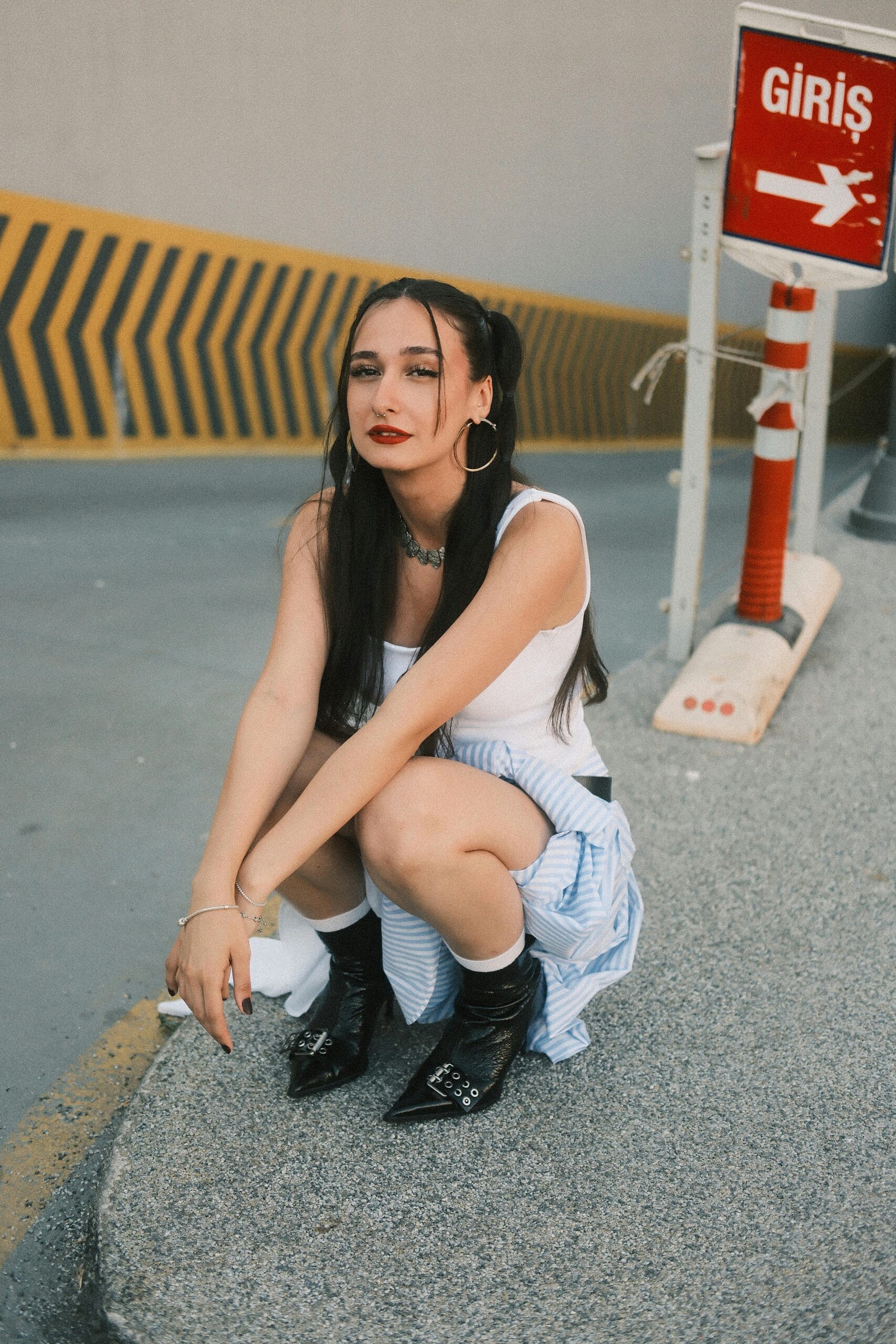 Young woman in trendy outfit poses stylishly in city setting.